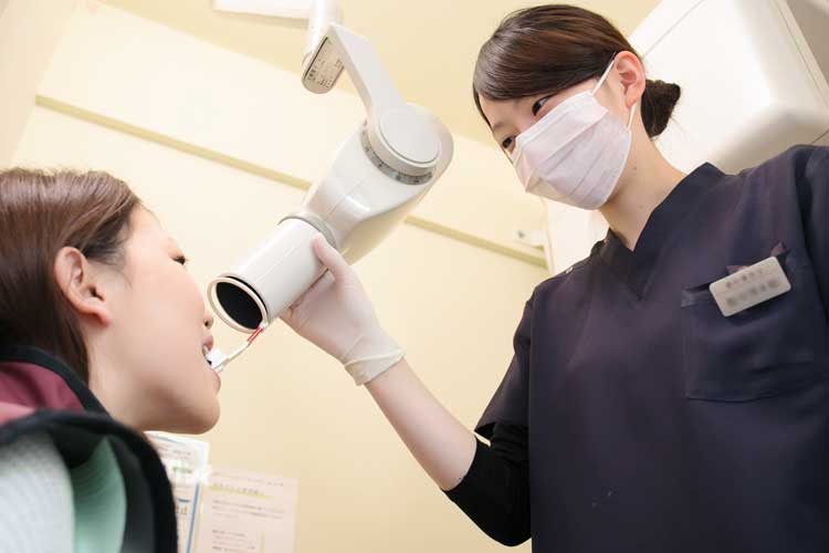 歯科用レントゲンで写真を撮ってる女性歯科衛生士